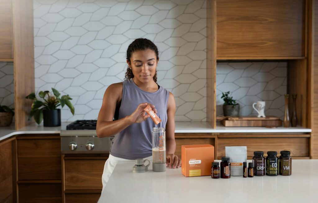 A woman uses essential oils and supplements in a contemporary kitchen for wellness.